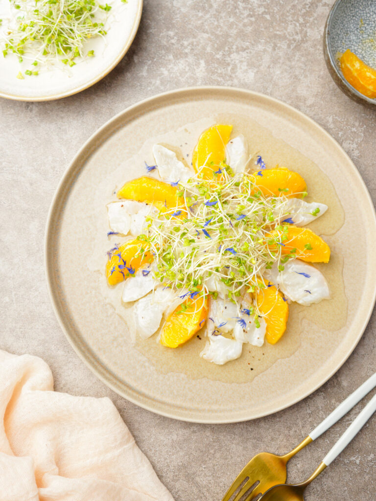 白身魚とオレンジのカルパッチョにスプラウトを添えた前菜