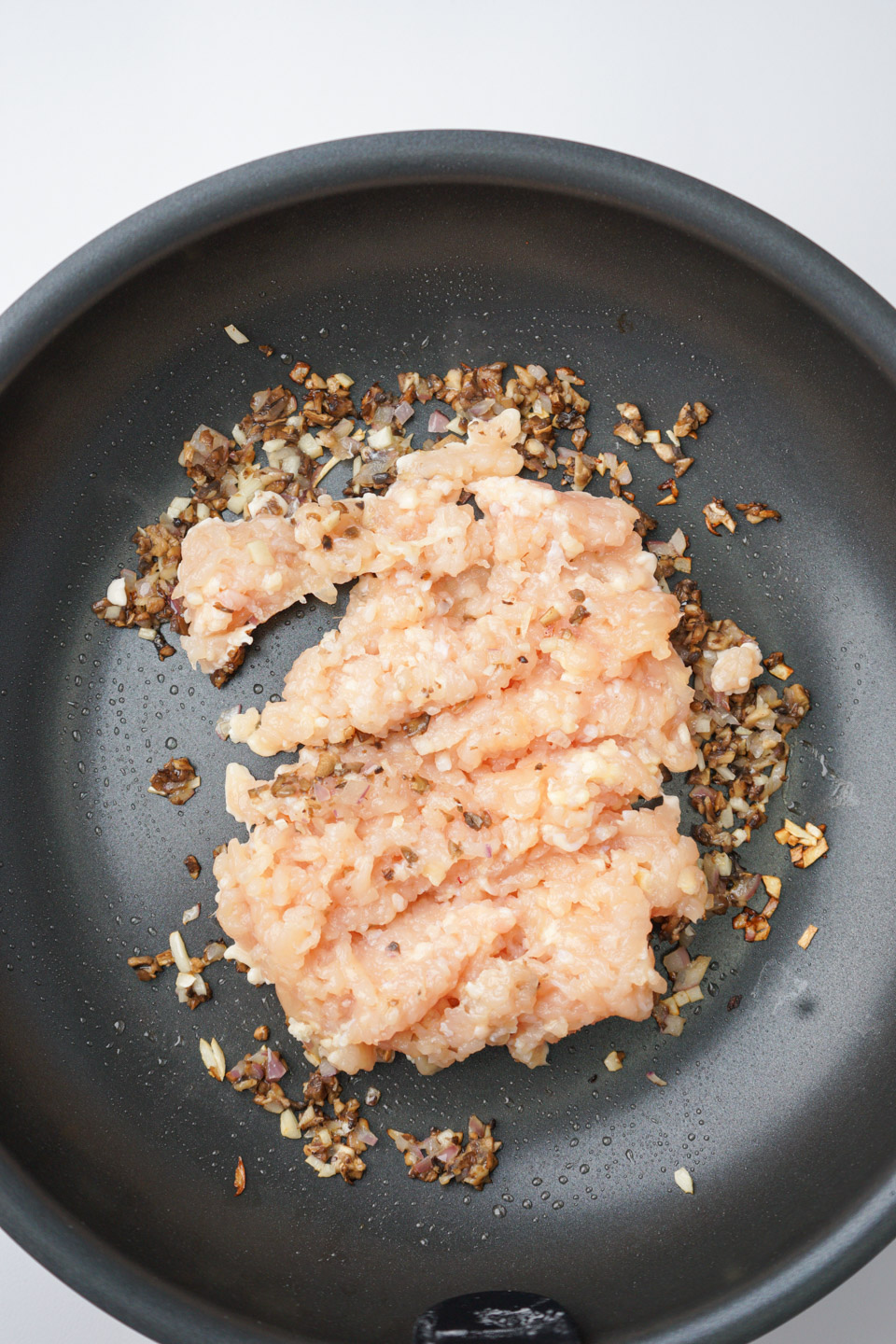 玉ねぎとマッシュルームを炒めたフライパンに鶏ひき肉を加える様子