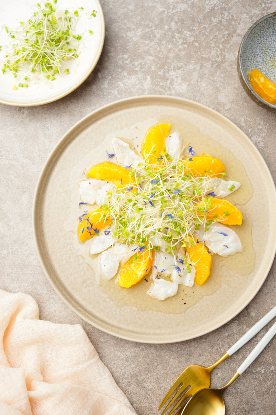 白身魚とオレンジのカルパッチョにスプラウトを添えた前菜