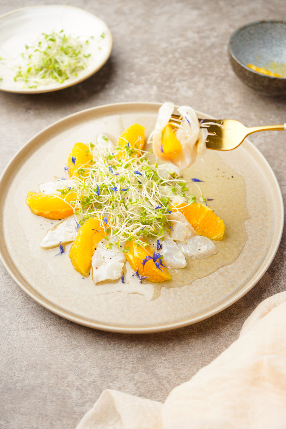 白身魚とオレンジのカルパッチョにスプラウトを添えた前菜