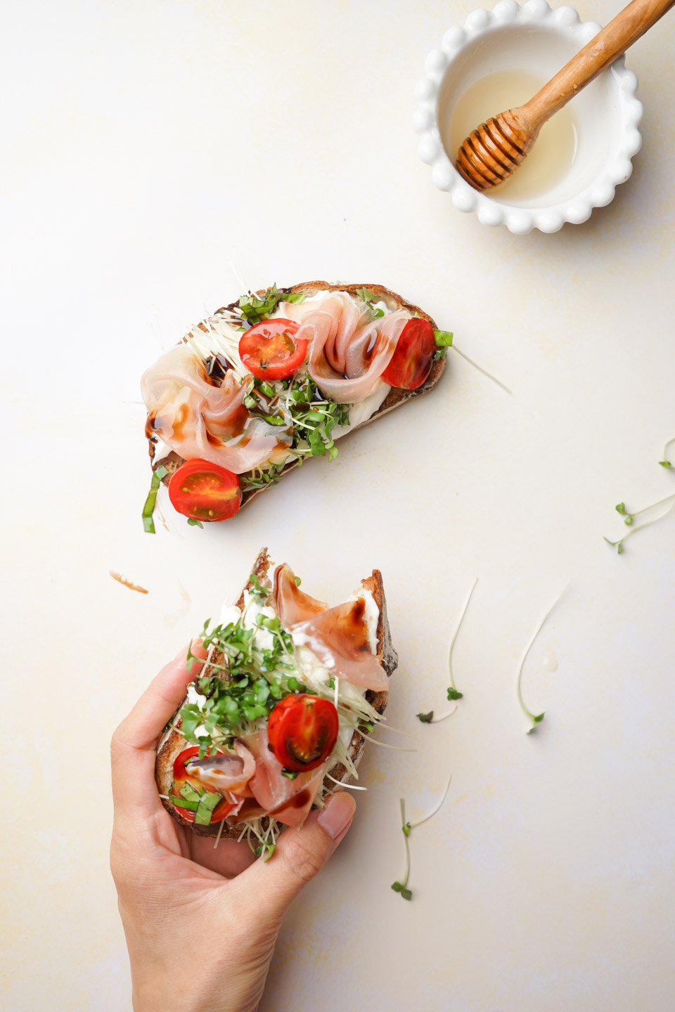生ハムとミニトマトのチーズトーストを手に持った様子