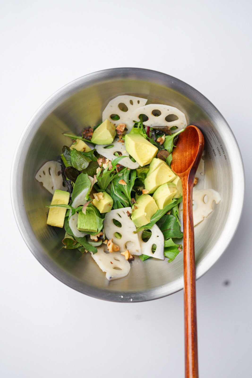 ボウルに薄切りれんこん、アボカド、ベビーリーフ、くるみを入れた、ドレッシングを加える前の状態
